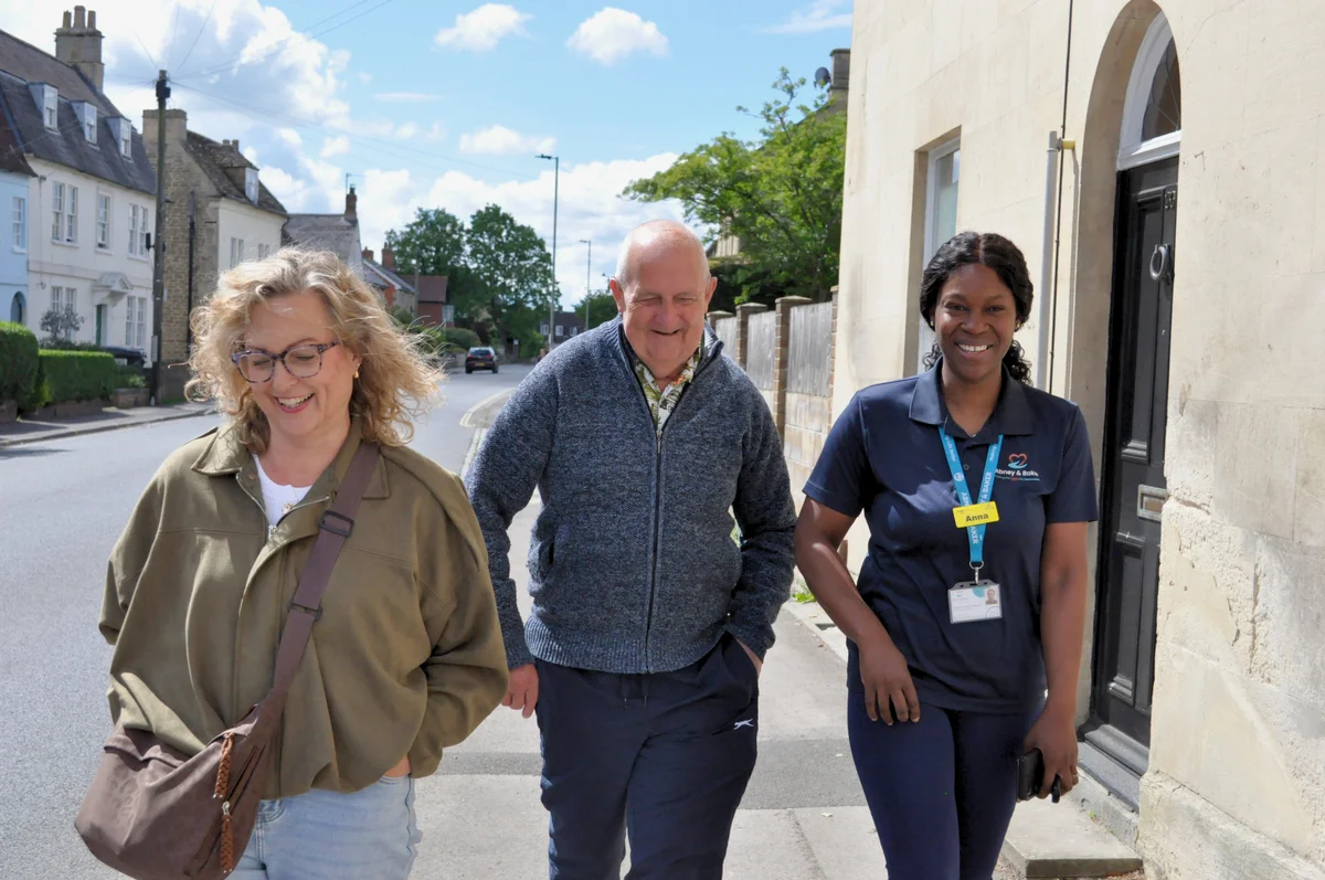 An Abney & Baker carer walking outdoors alongside two people