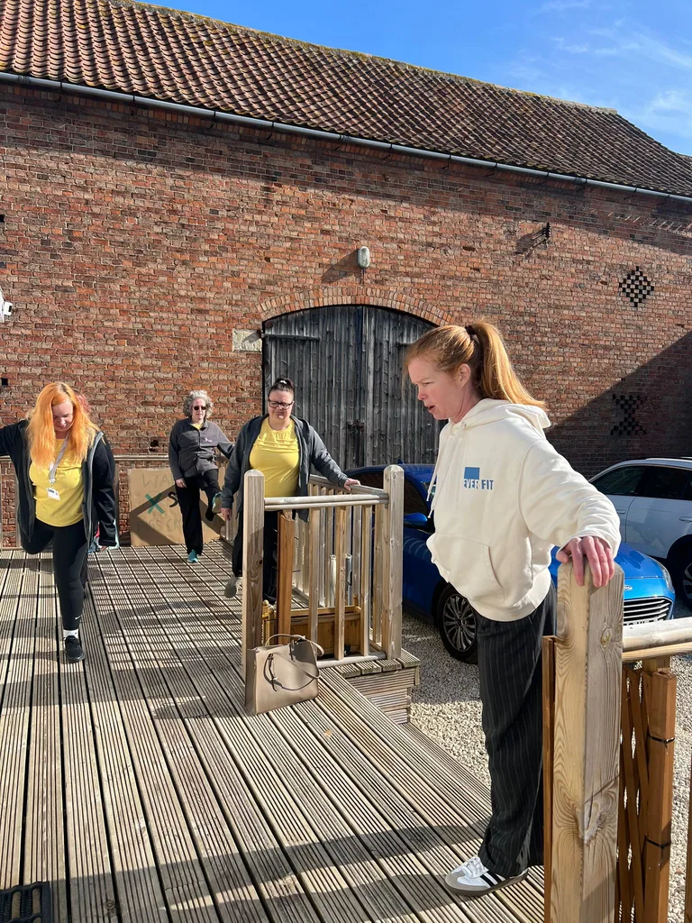 An EverFit instructor demonstrating a standing balance exercise outdoors with a group