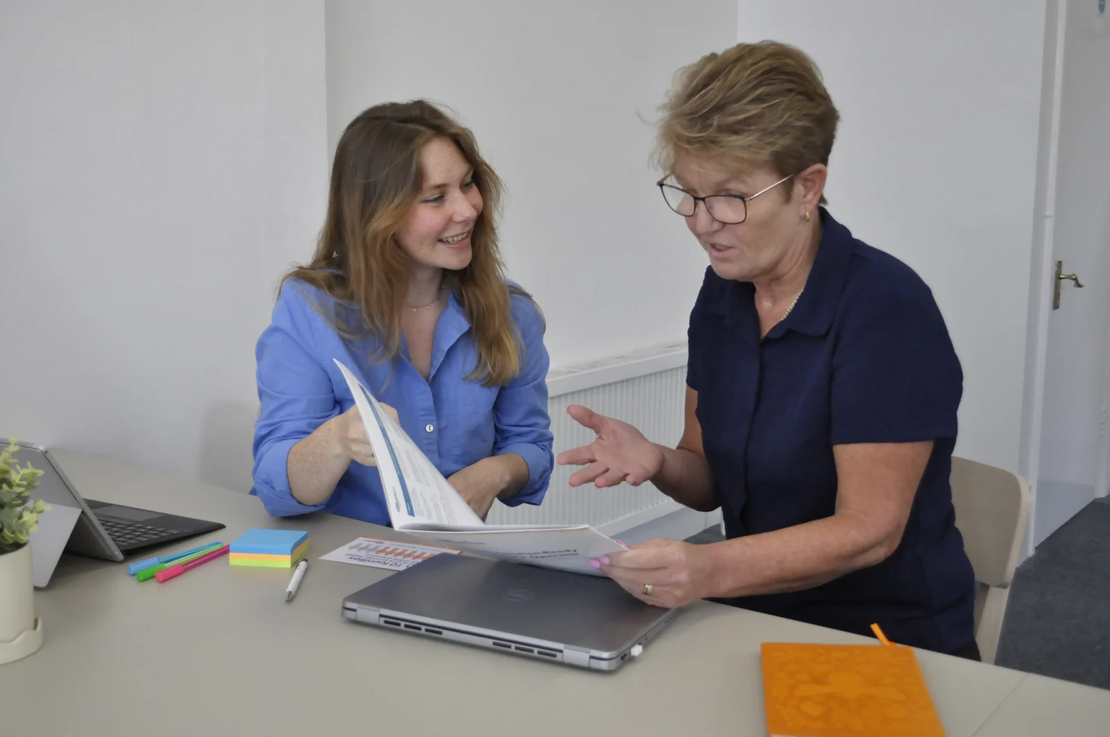 Two members of the Five Pillars team reviewing Programme materials together at an office table